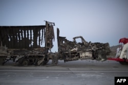 The scorched remains of a truck are towed at the North Fire, which caused people to abandon their vehicles and flee as flames jumped the 215 freeway near Victorville, California, July 17, 2015.