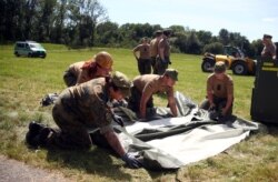 Prajurit Angkatan Bersenjata Jerman Bundeswehr membangun tenda untuk digunakan sebagai tempat tes Covid-19 di Landau an der Isar, di Jerman, 29 Juli 2020. (REUTERS / Michael Dalder)