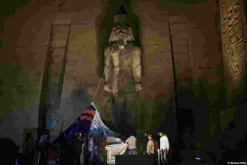 Egyptian Minister of Antiquities Khaled Al Anani, along with the restoration workers, removes the curtain as they celebrate the completion of King Ramses II colossus reconstruction project at Luxor temple in Egypt, April 20, 2018.