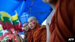 Seorang biksu mengenakan stiker bendera militer Myanmar di wajahnya saat pawai mendukung militer Myanmar di Yangon, 14 Oktober 2018.