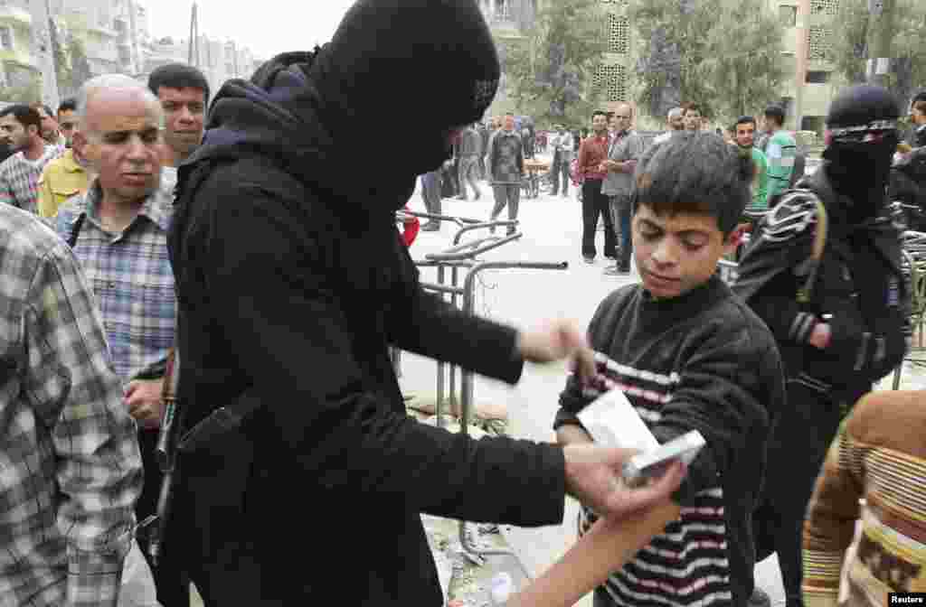 A fighter from the Islamist Syrian rebel group Jabhat al-Nusra searches a boy at the Karaj al-Hajez crossing in Aleppo, Nov. 7, 2013.