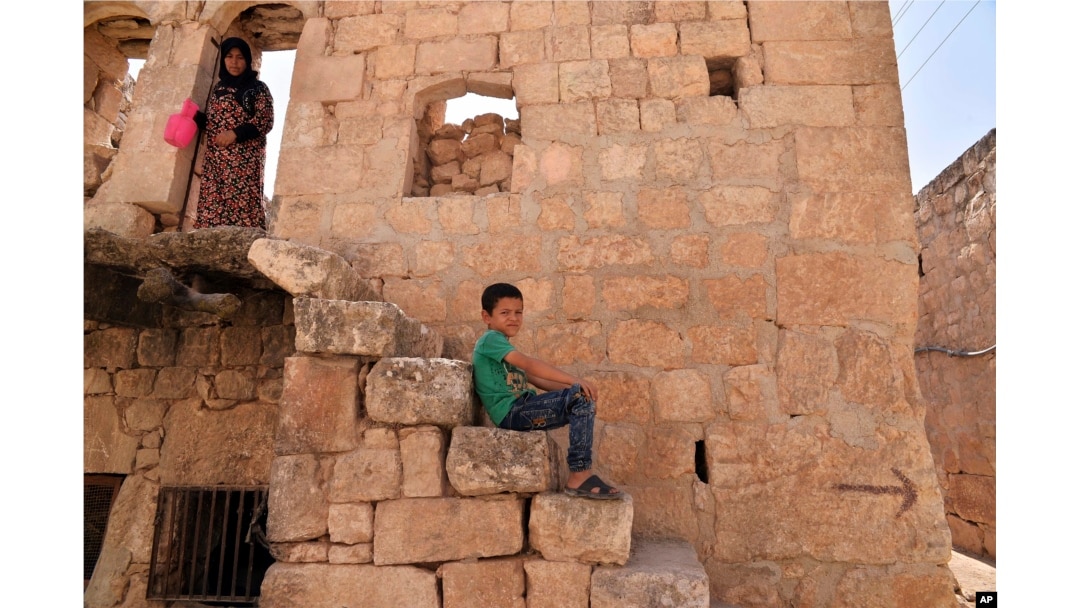 FILE - A child passes time in the northern town of Ariha, in Idlib province, Syria, Sept. 20, 2018.
