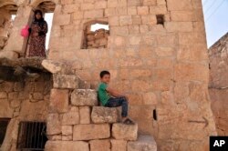 FILE - A child passes time in the northern town of Ariha, in Idlib province, Syria, Sept. 20, 2018.