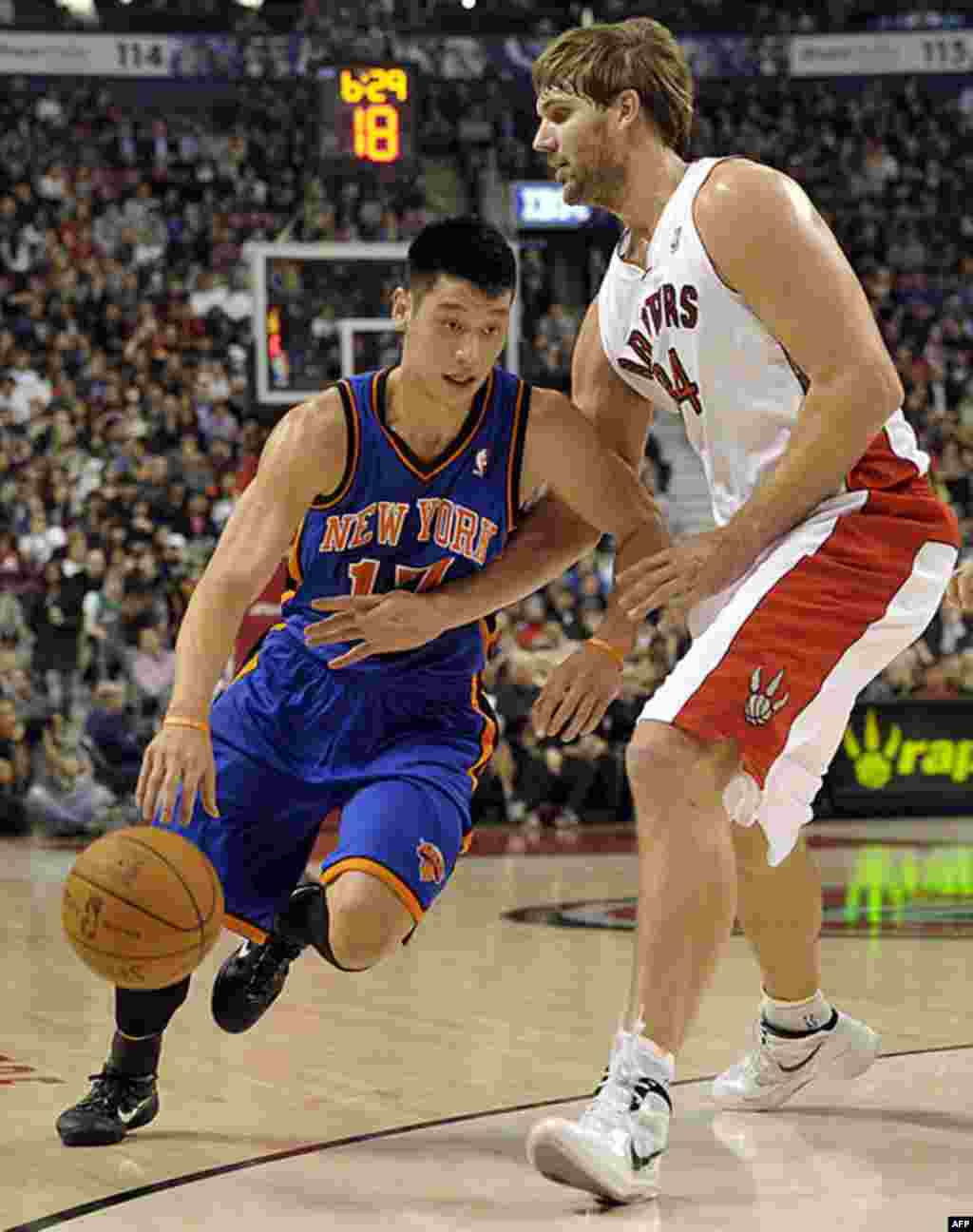 Jeremy Lin (trái), hậu vệ đội Knicks, nhồi banh về hướng rổ bên cạnh hậu vệ Aaron Gray của đội Roronto Raptors, trong trận đấu ở Toronto Canada, 14/2/12 (Reuters)