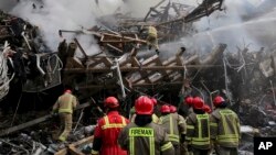 Iranian firefighters remove debris at the Plasco building which was engulfed by a fire and collapsed on Thursday, in central Tehran, Iran, Jan. 20, 2017.
