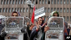 Women hold copies of Zaman newspaper with a headline that reads "the black day of democracy " as they protest against the detention of its editor-in-chief a day ago in Istanbul, outside the Palace of Justice in Ankara, Turkey, Dec. 15, 2014.
