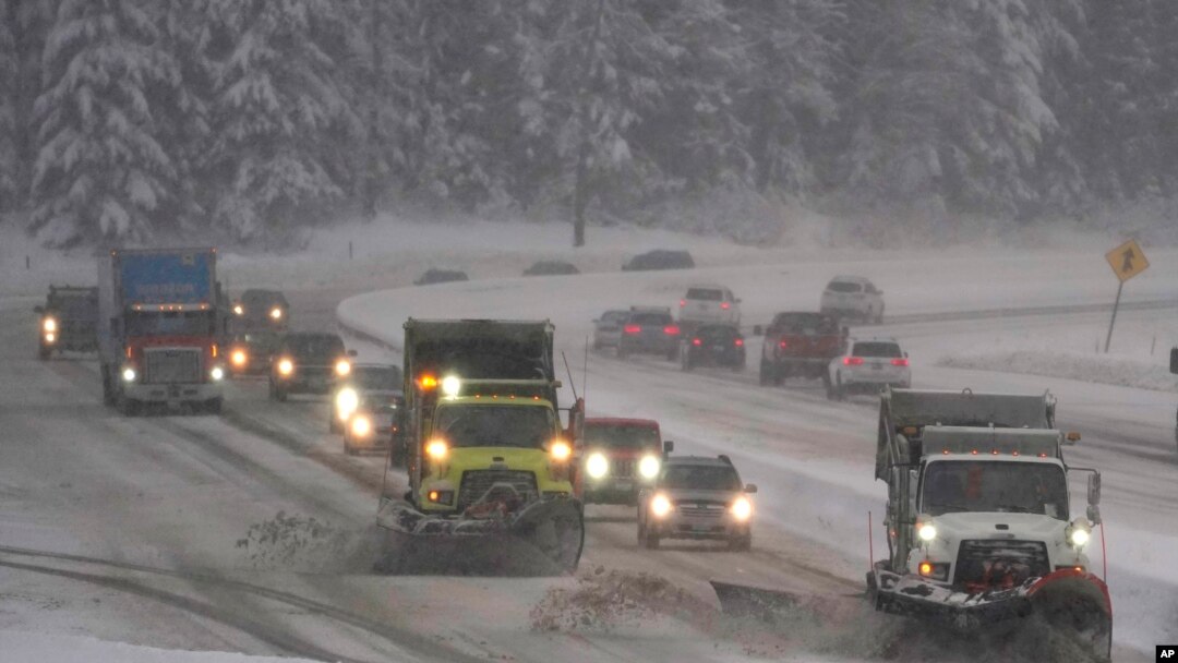 Washington Dept. of Transportation snow plows work on a stretch of eastbound Interstate Highway 90, Dec. 9, 2021, as snow falls near Snoqualmie Pass in Washington state.