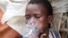 FILE - Abdulahi Yaroow, 13, smokes a cigarette while chewing khat at the same time in Mogadishu, Somalia, Aug. 10, 2014.