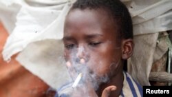 FILE - Abdulahi Yaroow, 13, smokes a cigarette while chewing khat at the same time in Mogadishu, Somalia, Aug. 10, 2014.