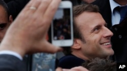 French independent centrist presidential candidate Emmanuel Macron shakes hands with well-wishers as he leaves the polling station after casting his ballot in the presidential runoff election in Le Touquet, France, May 7, 2017. 