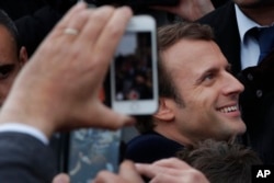 FILE - Emmanuel Macron, who at the time was a centrist candidate in France's presidential election, shakes hands with well-wishers as he leaves the polling station after casting his ballot in the presidential runoff election in Le Touquet, France, May 7, 2017.