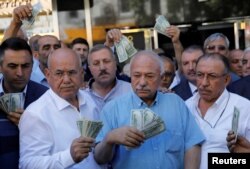 Businessmen holding U.S. dollars stand in front of a currency exchange office in response to the call of Turkish President Tayyip Erdogan on Turks to sell their dollar and euro savings to support the lira, in Ankara, Turkey Aug. 14, 2018.