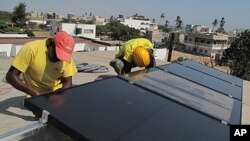 Prosolia technicians Mamadou Ba, left, and Mouhamed Diedhiou install solar panels on a vocational school in Dakar, Senegal, Dec. 1, 2011.