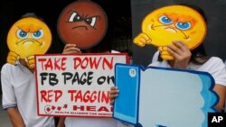 FILE - People covering their faces with "angry emoji" cutouts protest Facebook's alleged inaction against fake news, hate speech and red-tagging of activists, in suburban Taguig city, east of Manila, Philippines, May 9, 2019. 