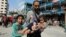 Seorang pria Palestina menggendong seorang anak yang terluka pasca serangan udara Israel terhadap sekolah PBB yang melindungi orang-orang terlantar, di tengah konflik Israel-Hamas, di Nusairat di Jalur Gaza tengah Senin (14/7). 