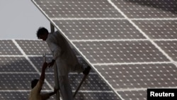 FILE - Technicians work on solar panel in power station at Hub about 25 km (15 miles) from Karachi, Pakistan.