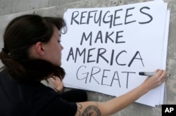 Protester Emily Nostro prepares a sign for a rally against President Donald Trump's executive order on Muslim immigration in downtown Miami, Jan. 22, 2017.