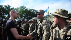 Ukrainian Prime Minister Arseniy Yatsenyuk (l) greets a soldier during inspection of a Ukrainian Army position outside the eastern town of Slovyansk, July 16, 2014. 