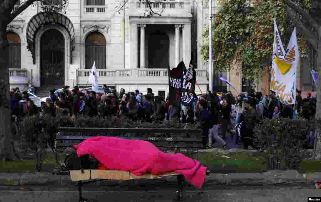 A homeless person sleeps as students take part in a demonstration to demand changes in the education system, in Santiago, Chile.
