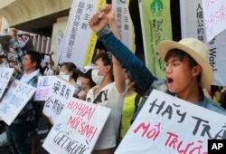 FILE - Vietnamese activists shout slogans and hold placards during a protest to urge Taiwan-owned steel plant Formosa Ha Tinh to take responsibilitiy for the clean-up of its toxic wastewater spill in Vietnam, in Taipei, Taiwan, Aug. 10, 2016.