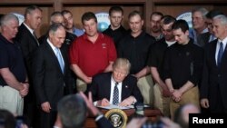 FILE -President Donald Trump signs an executive order eliminating Obama-era climate change regulations at the Environmental Protection Agency in Washington, March 28, 2017.