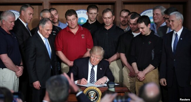 US President Donald Trump reacts after signing an executive order eliminating Obama-era climate change regulations at the Environmental Protection Agency in Washington, March 28, 2017.