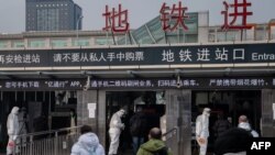 北京地鐵站保安人員身穿防護服檢測地鐵乘客的體溫。 （2020年1月27日）
