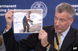 FILE - New York City Mayor Bill de Blasio displays a photo on Nov. 18, 2015, of a Syrian boy who drowned when his family tried to flee the war.