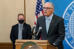 Washington Gov. Jay Inslee, right, speaks at a news conference, Aug. 18, 2021, at the Capitol in Olympia.
