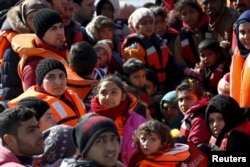 FILE - Refugees and migrants are seen on a dinghy as they approach the Ayios Efstratios Coast Guard vessel, during a rescue operation in the open sea between the Turkish coast and the Greek island of Lesbos, Feb. 8, 2016.