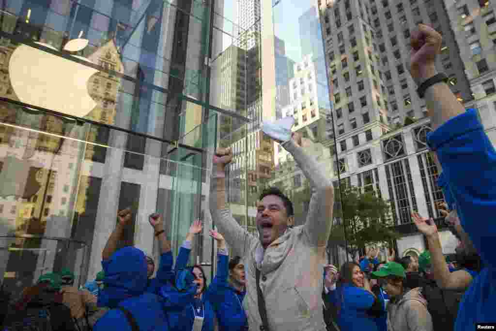 Local resident Andreas Gibson celebrates with employees outside the Fifth Avenue Apple store after being the first to exit with an iPhone 6 in hand on the first day of sales in Manhattan, New York. 