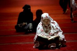 Seorang perempuan tengah membaca Al Qur'an di dalam masjid Istiqlal, Jakarta. (Foto: dok).