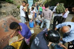 People collect water from an open pipeline during rolling blackouts, which affects the water pumps in people's homes and apartment buildings, in Caracas, Venezuela, Monday, March 11, 2019.