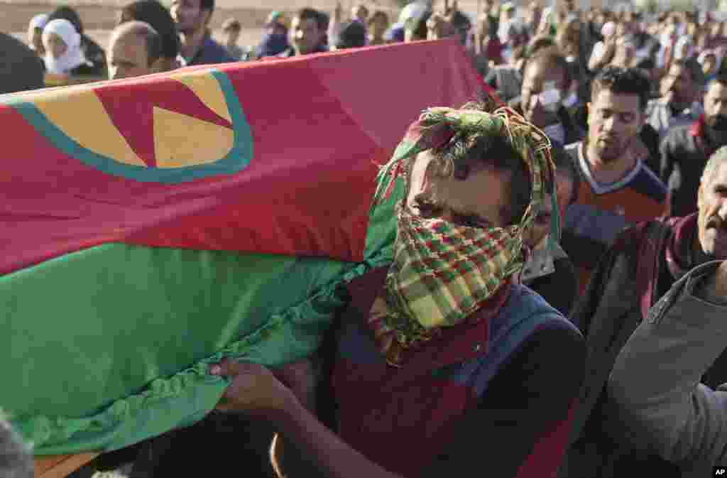 Kurdish men carry the coffin of YPG, or People's Protection Units, fighter Ahmed Mustafa, who died after being injured while fighting the Islamic State group forces in the Syrian city of Koban, Nov. 12, 2014.