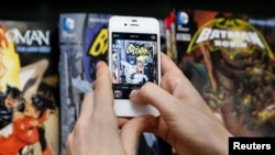 A man takes a photo of a Batman comic book during Batman Day at a comics store in New York July 23, 2014.