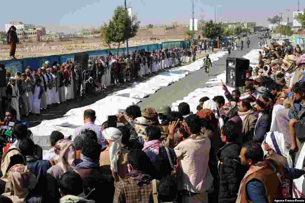 Onlookers gather as Yemenis pray during a mass funeral in Saada for those killed last weekend in airstrikes on a prison in the northern Yemeni province. At least 70 people were killed and more than 100 others wounded in the attack.