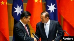 တရုတ်သမ္မတ Xi Jinping (ဝဲ) သြစတြေးလျဝန်ကြီးချုပ် Tony Abbott တို့ လွတ်လပ်စွာကုန်သွယ်ရေးသဘောတူစာချုပ် လက်မှတ်ထိုးပွဲမှာ တွေ့ရစဉ်။ (နိုဝင်ဘာ ၁၇၊ ၂၀၁၄) 