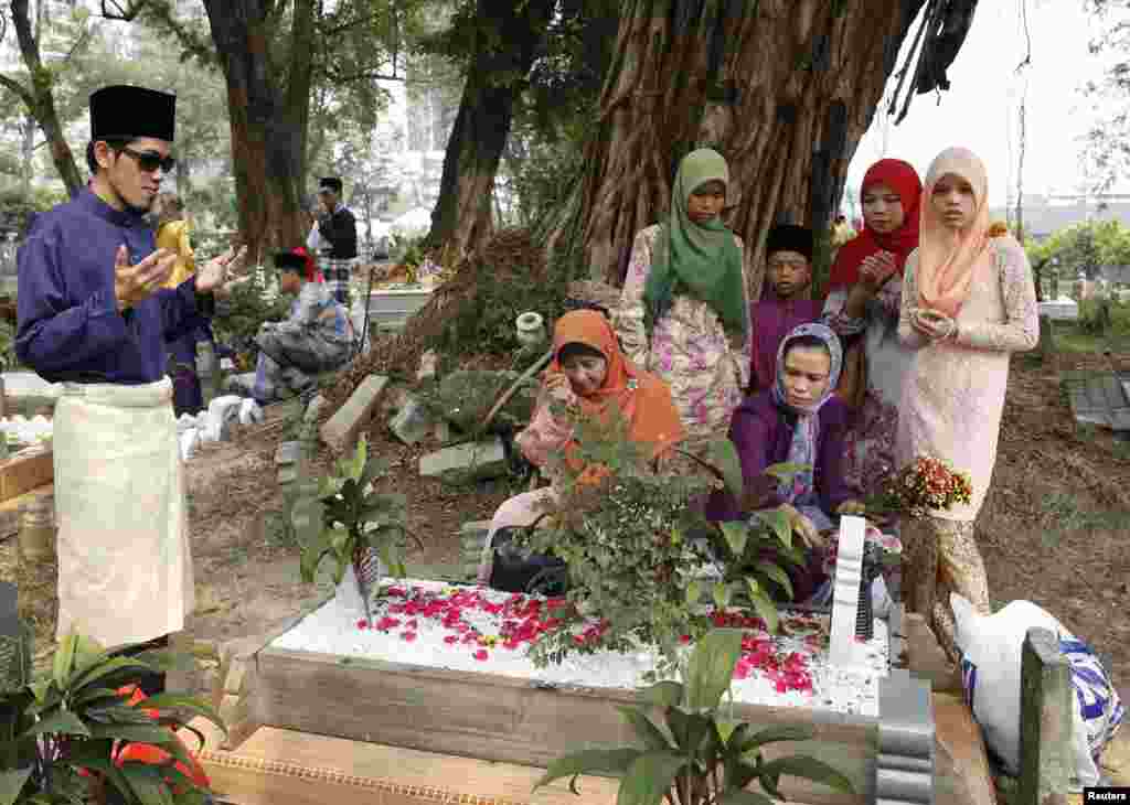 ملائیشیا میں عید کے موقع پر لوگ اپنے پیاروں کے لیے قبرستان میں فاتحہ خوانی کر رہے ہیں۔