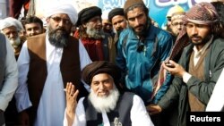 FILE - Khadim Hussain Rizvi, center, leader of the Tehreek-e-Labbaik Pakistan Islamist political party, gestures at a protest site at Faizabad junction in Islamabad, Pakistan, Nov. 27, 2017.