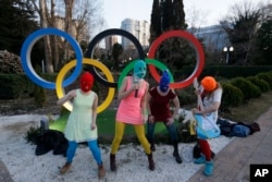 Members of the punk group Pussy Riot, including Nadezhda Tolokonnikova in the aqua balaclava, center, and Maria Alekhina in the red balaclava, left, perform next to the Olympic rings in Sochi, Russia, on Wednesday, Feb. 19, 2014.