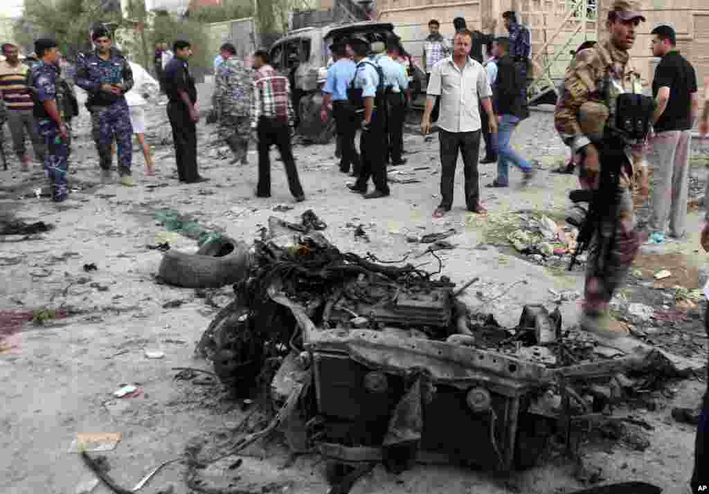 Security forces inspect the scene of a car bomb attack in Basra, Iraq, Jul. 14, 2013.