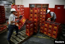 Employees carry beer boxes at a Regional warehouse in Caracas, Venezuela November 22, 2016.