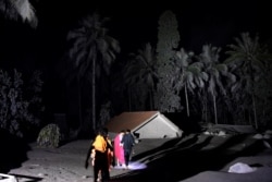 Warga berjalan di dekat rumah yang tertutup abu vulkanik yang dimuntahkan Gunung Semeru di Desa Sumber Wuluh, Lumajang, Jawa Timur, 5 Desember 2021. (Foto: Antara/Zabur Karuru via REUTERS)