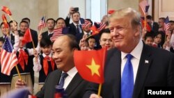 Tổng thống Donald Trump (phải) vẫy lá cờ Việt Nam trong khi Thủ tướng Phúc vẫy lá cờ Mỹ tại một buổi đón tiếp nguyên thủ Mỹ ở Văn phòng Chính phủ ở Hà Nội hôm 27/2.