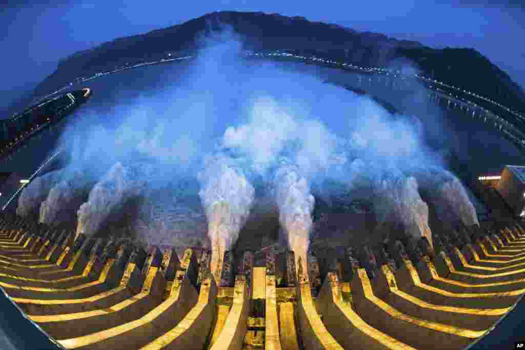 In this image made with fisheye lens and provided by Xinhua News Agency, floodwaters are discharged at the Three Gorges Dam in central China's Hubei province, July 19, 2020.