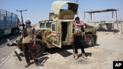 ISIL militants stand with captured Iraqi Army Humvee at a checkpoint outside Beiji refinery, north of Baghdad, Iraq, Thursday, June 19, 2014. 