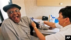 Archbishop Desmond Tutu, left, reacts as he is examined by a clinical nurse inside the 'Tutu Tester' mobile unit in Cape Town, South Africa, Thursday Oct. 22, 2009. The Tutu Tester, is a mobile unit that test people for diabetes, obesity and HIV with resu