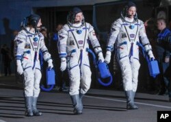 US astronauts Christina Hammock Koch (L), Nick Hague (R), and Russian cosmonaut Alexey Ovchinin, members of the main crew of the expedition to the International Space Station (ISS), walk before the launch of Soyuz MS-12 space ship at the Russian-leased Baikonur cosmodrome, Kazakhstan, March 14, 2019.