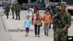 Pedestrians walk along a street guarded by soldiers in the Soacha district, southern Bogota, Colombia, Aug. 30, 2013. 