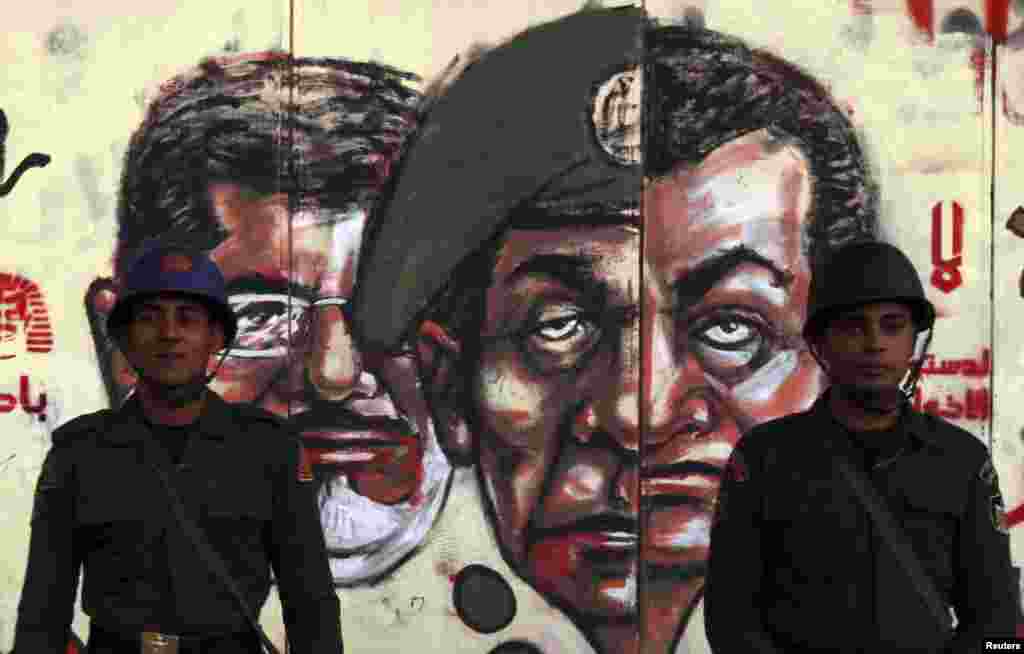 Republican Guard soldiers stand in front of a mural depicting Egypt's former President Hosni Mubarak (R), former Field Marshal Mohamed Hussein Tantawi (C) and Egypt's President Mohamed Mursi drawn on the wall of the presidential palace in Cairo December 1.
